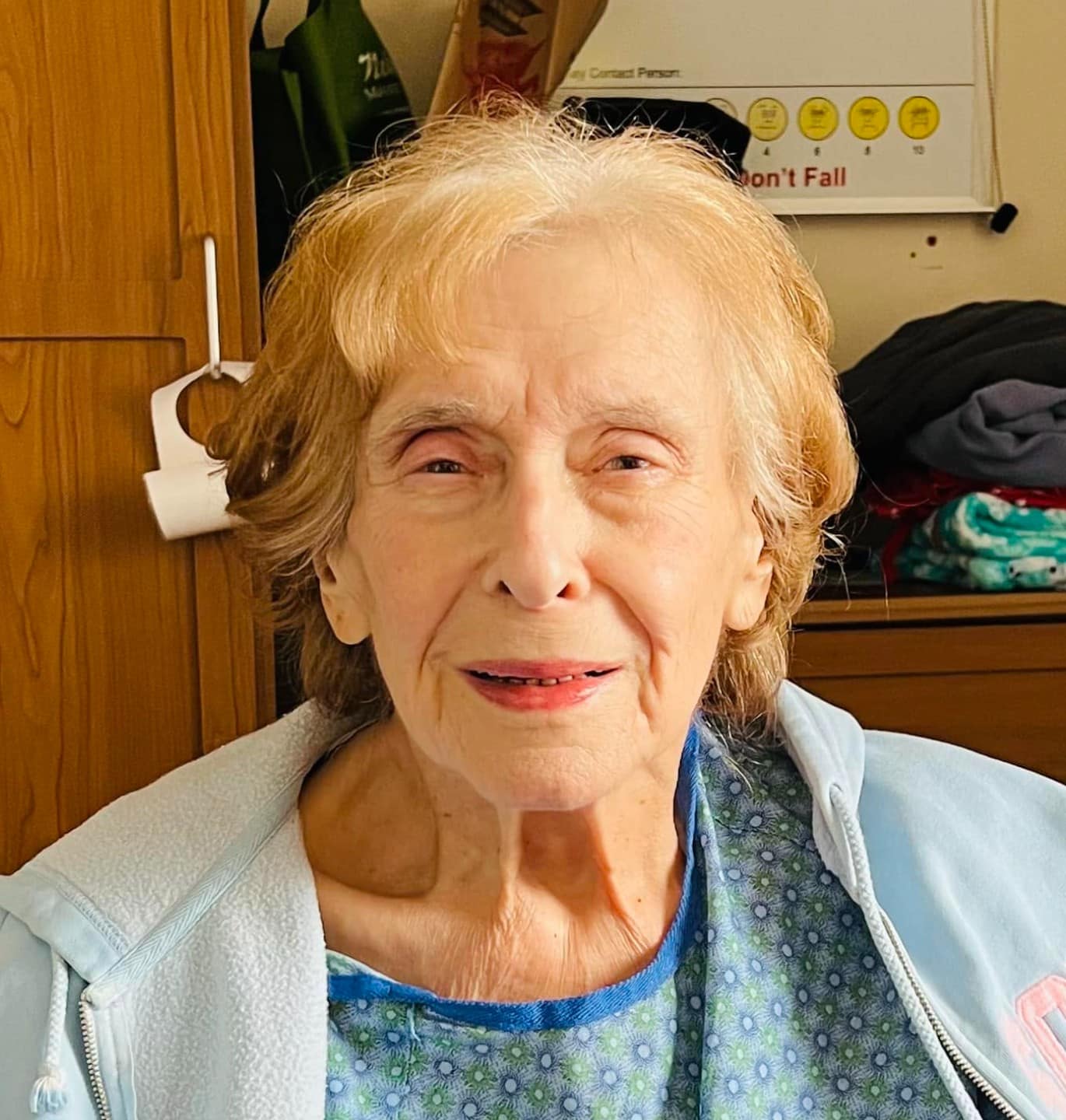 Elderly woman with soft silver hair and an unguarded, gentle expression, resting in a hospital setting